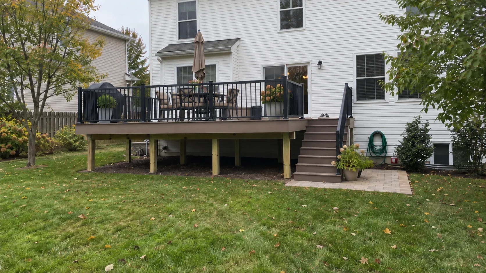A garden view looking up at a raised deck finished with dark metal railings