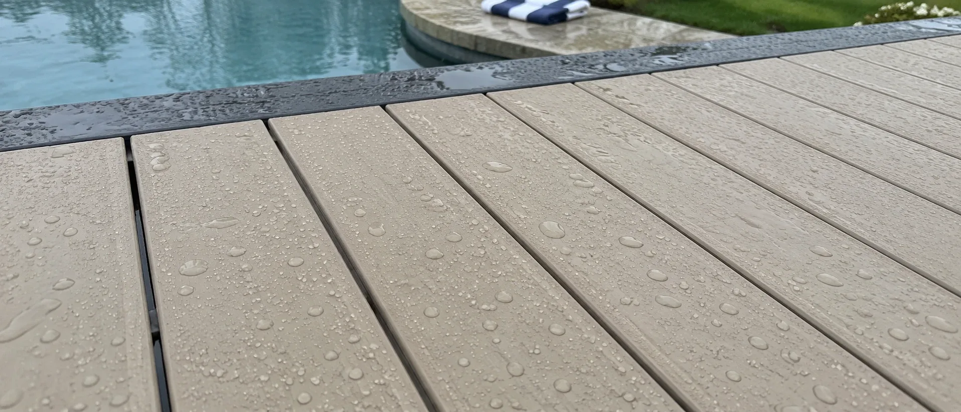 Droplets resting on light PVC boards instead of soaking in, with a pool edge just beyond